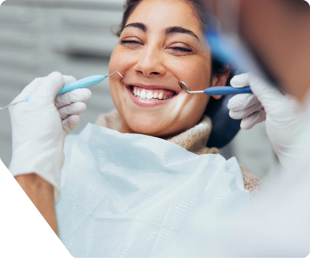 A woman smiling while a dentist performs a checkup.