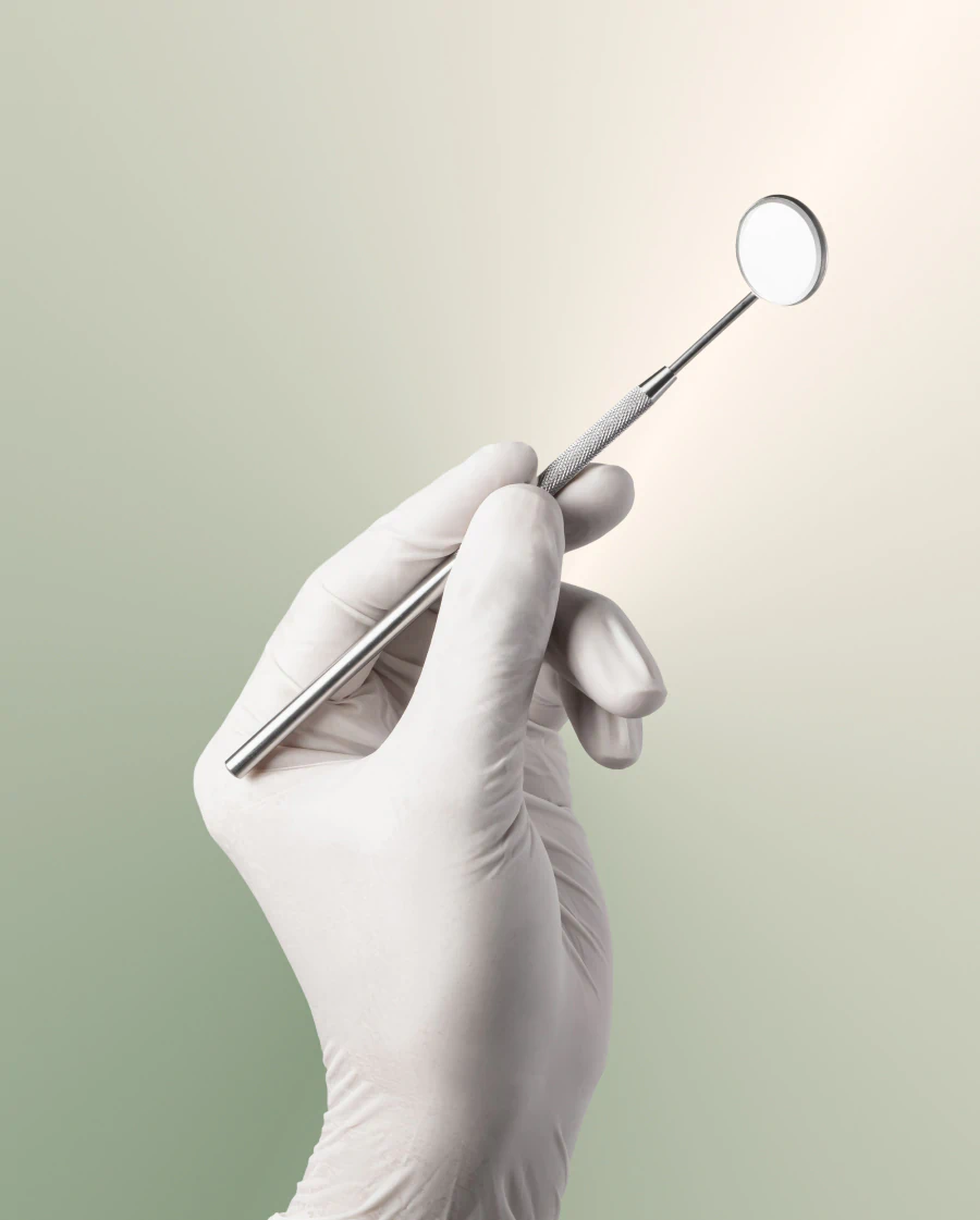 A hand wearing a white medical glove holding a dental mirror.