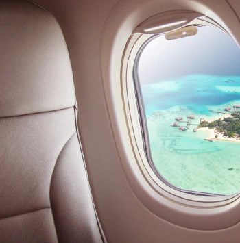 View of a tropical island resort with overwater bungalows from an airplane window.