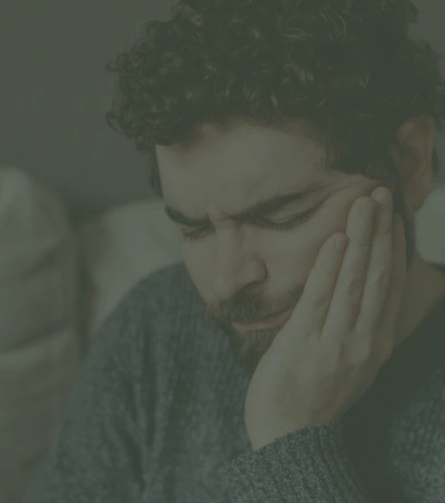 A person holding their hand to their cheek, appearing to be in pain.